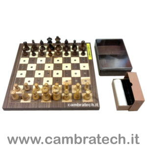 Immagine della scacchiera magnetica con disposte sopra ad essa le pedine degli scacchi; di fianco a destra la custodia con le dame e la custodia vuota degli scacchi.